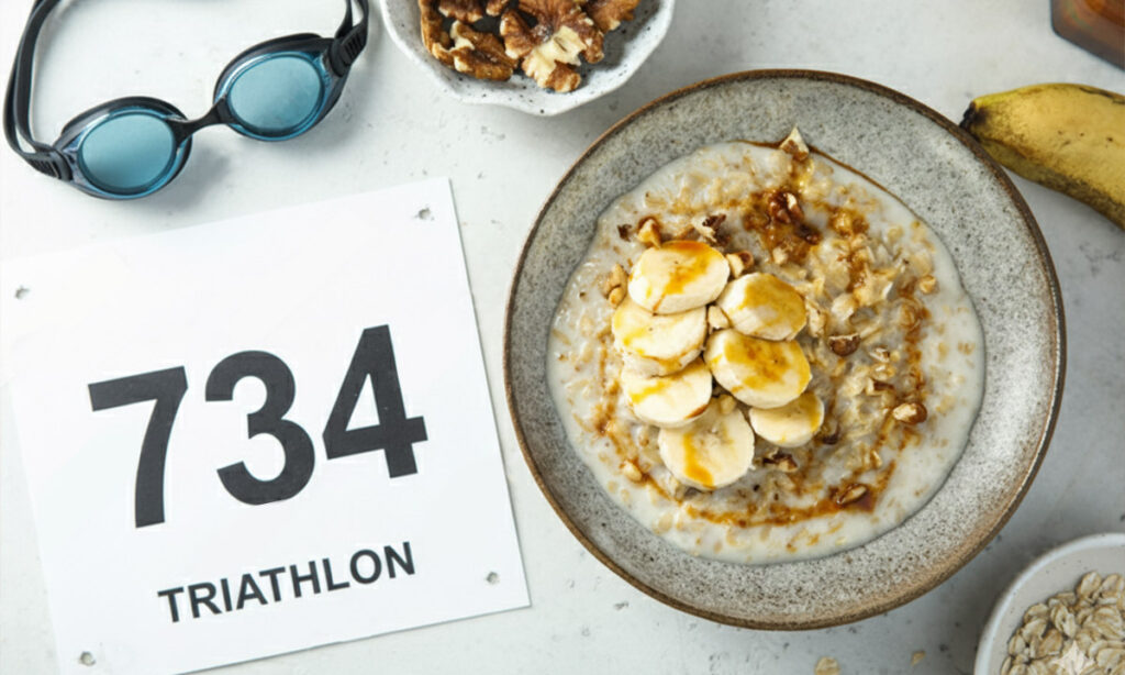 A bowl of oatmeal and a banana on a table beside a triathlon race bib and swim goggles