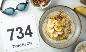 A bowl of oatmeal and a banana on a table beside a triathlon race bib and swim goggles