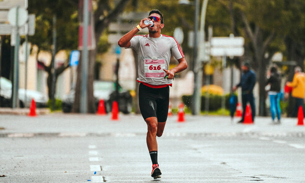 Endurance athlete drinking from a sports bottle mid-race, illustrating sodium intake during a race
