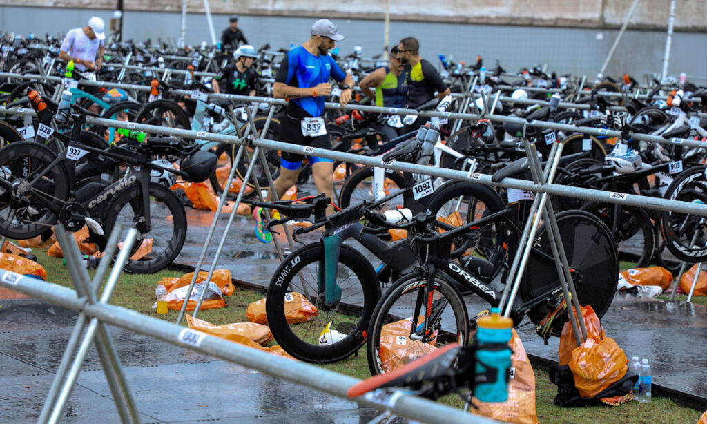 athlete running through triathlon transition area with bikes and gears laid out