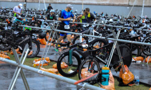 athlete running through triathlon transition area with bikes and gears laid out