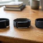 Three screenless fitness trackers side by side on a desk