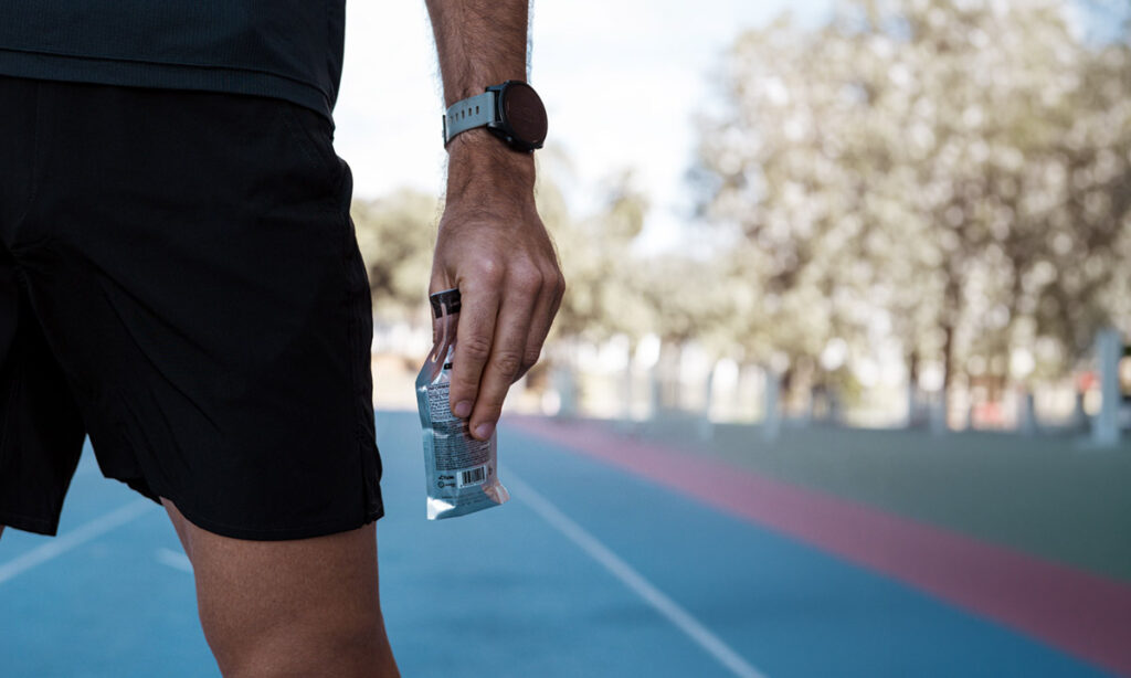 runner holding an energy gel packet on a track, illustrating the new lactate gels trend