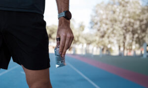 runner holding an energy gel packet on a track, illustrating the new lactate gels trend