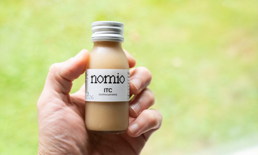 Hand holding a bottle of Nomio broccoli sprout shot, tested for this does Nomio work review
