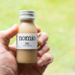 Hand holding a bottle of Nomio broccoli sprout shot, tested for this does Nomio work review