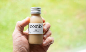 Hand holding a bottle of Nomio broccoli sprout shot, tested for this does Nomio work review