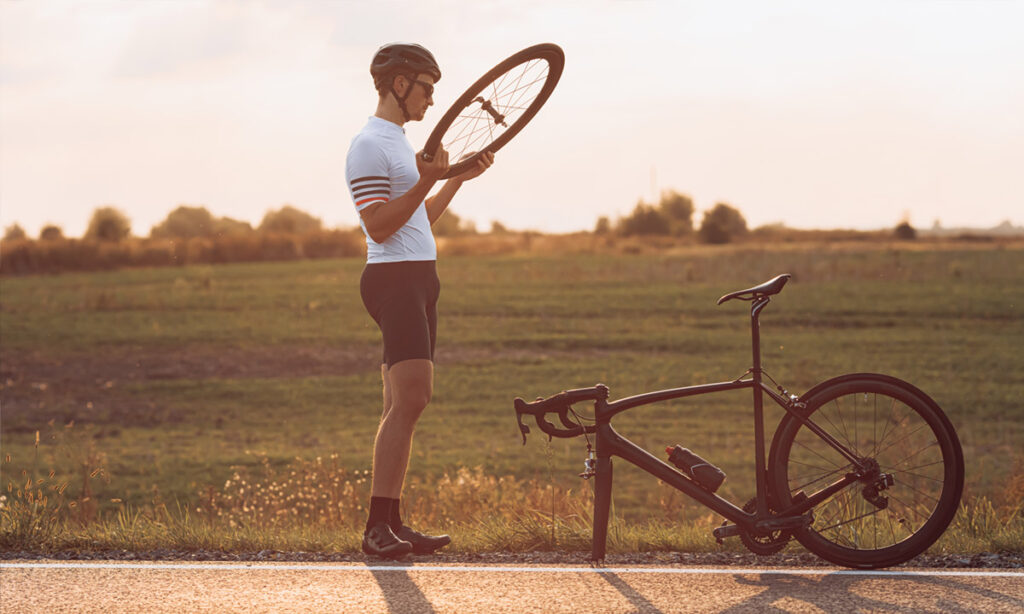cyclist checking broken bike by side of the road