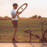 cyclist checking broken bike by side of the road