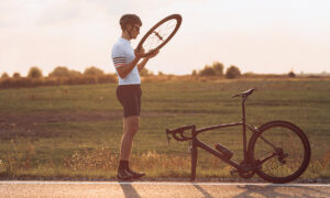 cyclist checking broken bike by side of the road