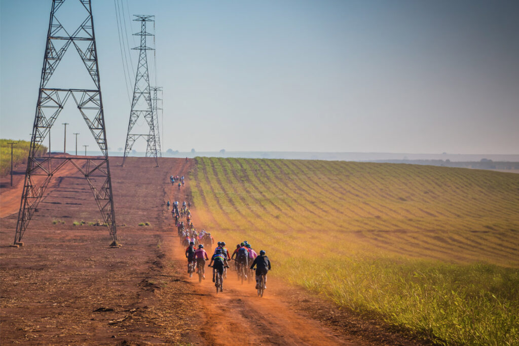 Pack of cyclists gravel racing through dust on a dirt road