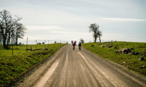 Group of cyclists gravel racing down a rural dirt road