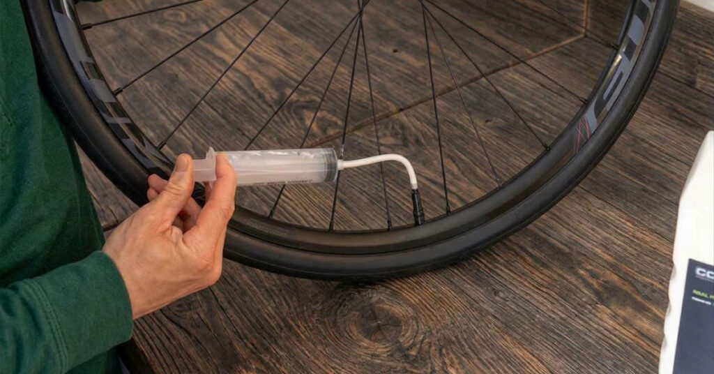 Syringe injecting tubeless sealant through a presta valve