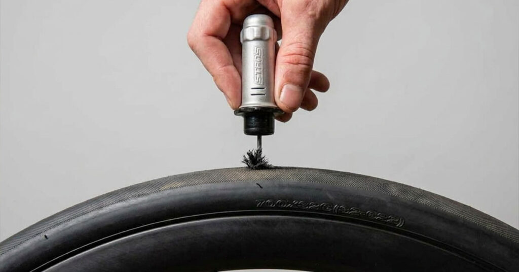 tubeless tire repair dart tool next to a road tire